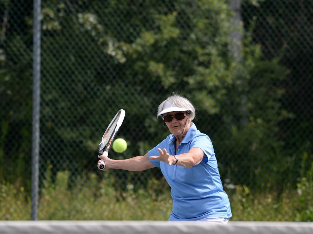 Une dame âgée s'apprête à frapper un eballe de tennis