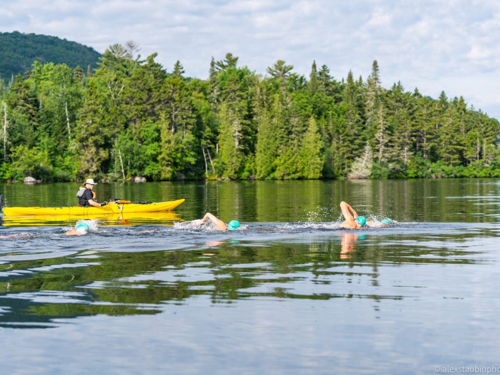 un kayakiste suit des nageurs sur le lac