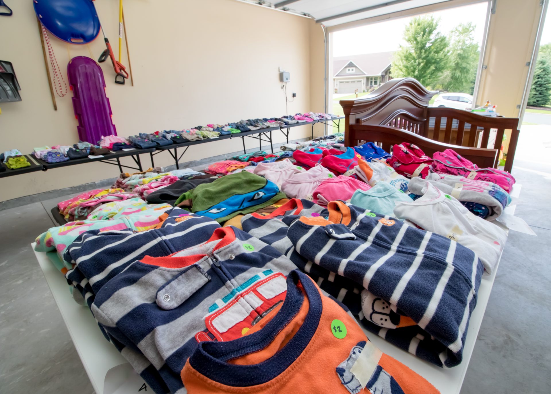 Des piles de vêtements bien pliés sont étiquetés et déposés sur une table dans un garage.